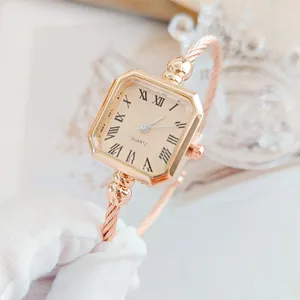 Orologio al quarzo quadrato in oro rosa con numeri romani e bracciale a corda intrecciata.