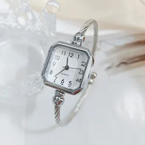 Primo piano dettagliato del quadrante quadrato e del cinturino in metallo dell'orologio.