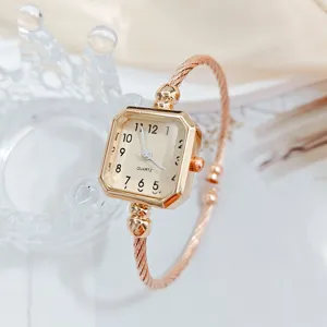 Dettaglio dell'orologio quadrato da donna con quadrante elegante e bracciale a cavo.