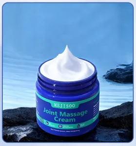 Close-up detail view of white joint massage cream texture inside a blue jar on dark rock.