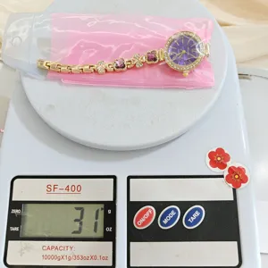 Detail shot of gold quartz watch with purple dial and clover link bracelet design.