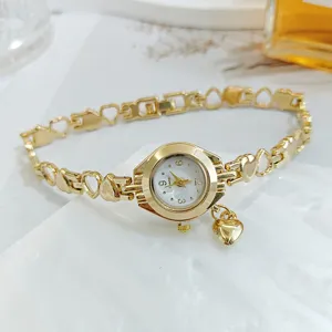 Nahaufnahme der eleganten goldfarbenen Quarzuhr mit Herz-Armbandgliedern und Anhänger.
