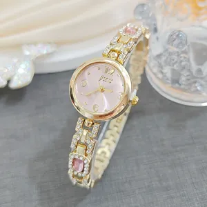 Close-up detail of luxury women rhinestone quartz watch featuring pink dial and gold link bracelet.