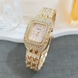 Luxury gold square rhinestone women quartz watch close-up detail, pink dial shining crystal strap.