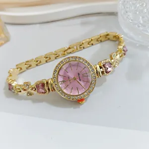 Close-up detail of the gold-tone quartz watch, featuring a pink crystal dial and rhinestone bezel.