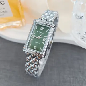 Detailansicht einer schicken rechteckigen Damenuhr mit grünem Zifferblatt und Metallarmband.