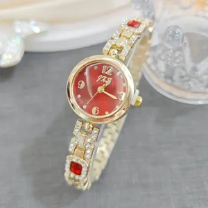 Detail shot of women's gold quartz watch with red dial, rhinestones, and elegant bracelet strap.
