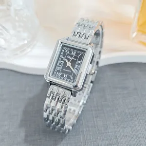 Detailed close-up shot of a silver square quartz watch featuring a black Roman numeral dial.