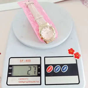 Close-up detail of women quartz watch with pink strap and diamond dial on electronic scale.