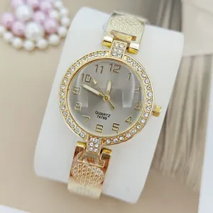 Detailansicht einer goldenen Quarzuhr mit Strasssteinen, elegantem Zifferblatt und Kristallen.