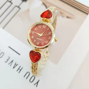 Elegant women quartz watch featuring red heart crystal charms and gold metal bracelet.