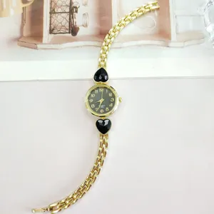 Elegant gold quartz watch for women featuring chic black heart stone accents and slim bracelet strap.
