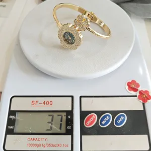 Vue détaillée montre fleur strass dorée, elegant bracelet sur balance affichant 37g.