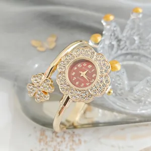 Détail en gros plan d'une montre florale en strass luxueuse avec cristaux et finition dorée.