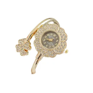 Luxueuse montre bracelet jonc fleurie avec strass pour femme, élégante montre quartz dorée.