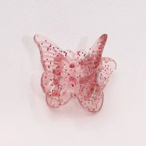 Close-up detail of a cute mini butterfly hair claw clip with pink glitter jelly design for styling.
