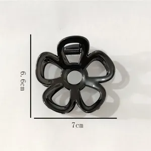 Close-up detail view of the black geometric flower hair claw clip, highlighting size.