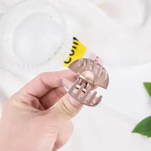Primo piano dettagliato della mini molletta per capelli in ABS, forma rotonda e metallizzata.