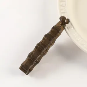 Detailed view of a dark brown plastic banana clip with irregular wave design for daily wear.