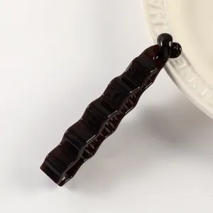 Detailed close-up of the dark brown tortoiseshell banana hair clip, showing irregular wavy texture.
