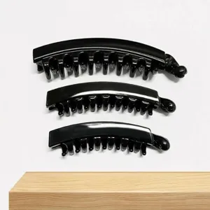Detail shot of black glossy banana hair clip, minimalist style, smooth surface texture.