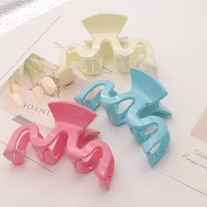 Detailed close-up of wavy plastic hair claws in pastel pink, blue, and cream colors.