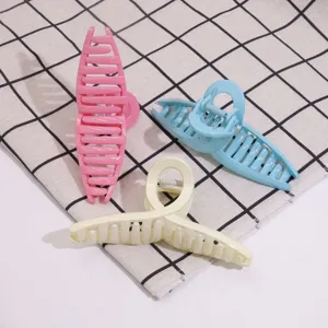 Close up view of stylish plastic hair claws in pink, blue and cream, featuring cutout designs.