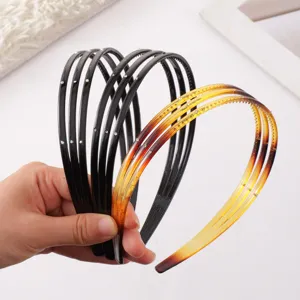 Closeup of thin plastic tooth headbands with rhinestones, black and amber gradient colors.