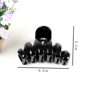 Close-up detail of the elegant black hair claw clip, showing its unique spiral design and size.