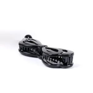Close-up detail of black plastic banana hair clip, stylish vertical hollow mesh hair accessory.