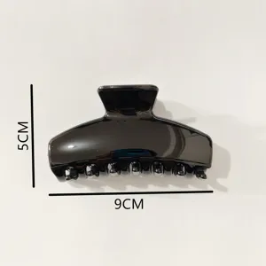 Black plastic hair claw clip detail close-up shot, minimalist daily hair styling accessory.