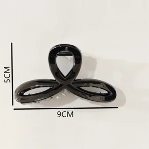 Glossy black plastic hair claw clip detail view, featuring simple geometric style and 9cm size.