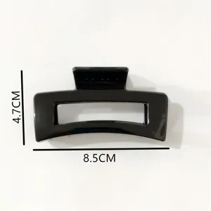 Detail view of the glossy black rectangular hollow plastic hair claw clip with specs.