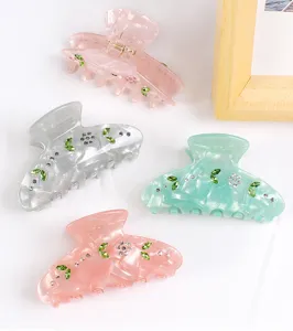 Schicke Acryl Haarklammer mit funkelnden Strasssteinen und grünen Blättern, modisches Design.