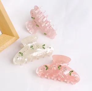Detailansicht einer eleganten Acryl Haarklammer mit funkelnden Strasssteinen und Blumenblatt.