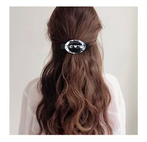 Vista dettagliata di un elegante fermaglio per capelli in acrilico nero e bianco sui capelli lunghi.