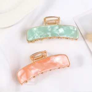 Eleganti pinze per capelli a mezzaluna in acrilico verde e rosa con denti in metallo dorato.