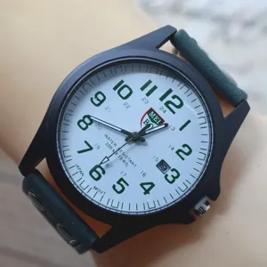 Close up view of men military quartz watch dial, white face with green numbers and date window.
