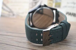 Detailed close-up shot of the green perforated leather watch strap and metal buckle.