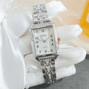 Détail de gros plan de montre quartz pour femme carrée de luxe en strass avec bracelet en acier.