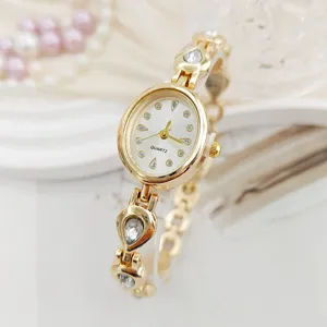 Close-up detail of luxury gold women watch featuring teardrop crystal charms and white dial.