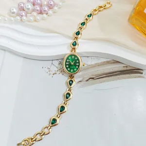 Luxury women's quartz watch with green teardrop stones, elegant gold bracelet design for daily wear.