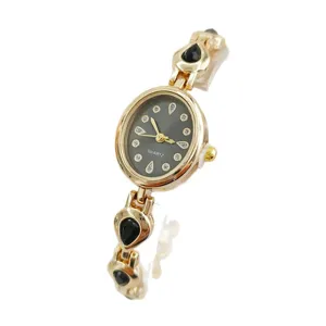 Gold-tone quartz women's watch with teardrop black stones and crystal dial for daily wear.