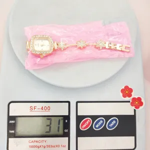 Detailansicht der quadratischen Strass-Damenarmbanduhr auf einer Waage, 31g schwer.