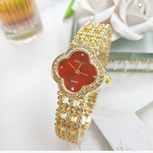 Primo piano dell'orologio da donna al quarzo con trifoglio in strass dorato, dettagli brillanti.