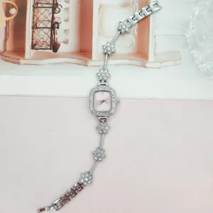 Detaillierte Nahaufnahme des quadratischen Strass-Zifferblatts und floralen Armbanddetails.