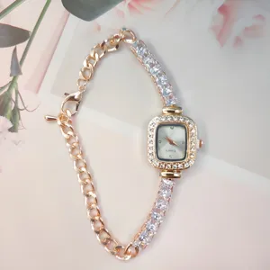 Detail shot of elegant women rhinestone square watch with golden chain bracelet and quartz movement.