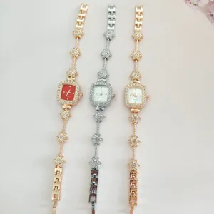Detailansicht modischer Damen Quarz-Uhr mit quadratischem Zifferblatt und Strass Blumenarmband.