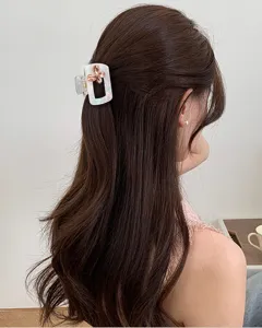 Vista dettagliata di un'elegante molletta per capelli rettangolare bianca con fiori di strass.