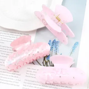 Dettaglio molletta per capelli in acrilico rosa con strass, stella marina e bei fiocchi.